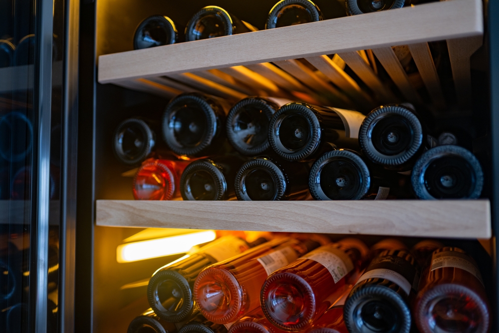 Illuminated,wine,cellar,shelf,with,bottles,in,warm,light,and